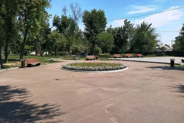 Сонячний сквер «Амурський парк» із круглою клумбою, лавами й зеленими деревами