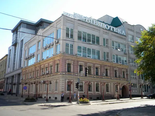 Зелений фасад Центральної міської бібліотеки Дніпра з великим написом «БІБЛІОТЕКА» та кількома перехожими вдалині