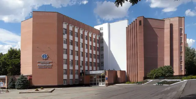 Червоноцегляний корпус університету внутрішніх справ із назвою закладу та емблемою на глухій стіні, ґанком входу й брукованим майданчиком