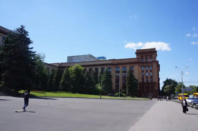 Просторий літній вигляд площі Героїв Майдану в центрі Дніпра з деревами й кількома перехожими вдалині
