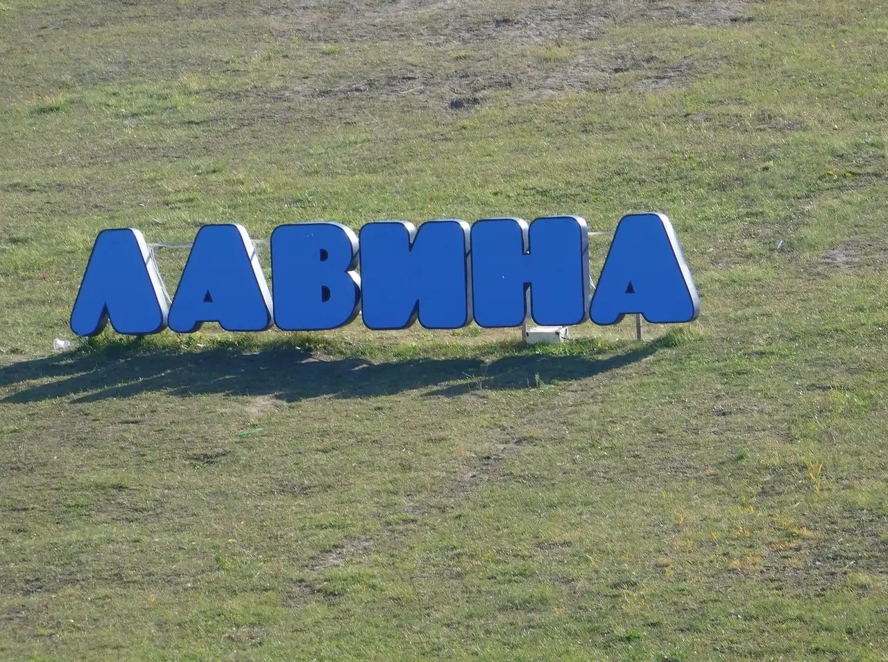 Великі сині літери «Лавина» на зеленому схилі парку розваг у Дніпрі