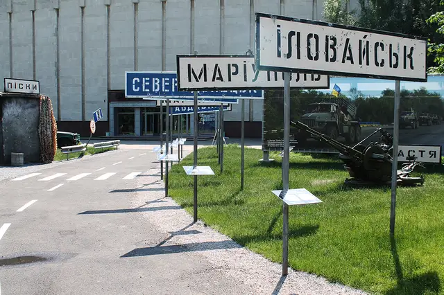 Вулична експозиція Музею АТО у Дніпрі з дороговказами, технікою і входом до корпусу