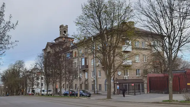 Ділянка вулиці Михайла Грушевського з трамвайними коліями та будинком із вежею у квітні 2026 року