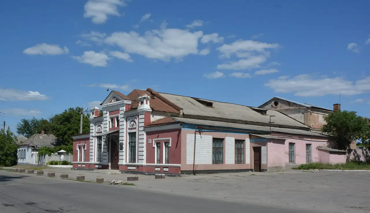 Історична рожево-біла будівля павлоградського театру з декорованим фронтоном, кутовим входом і датою спорудження на аттику