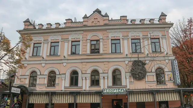 Історичний рожевий фасад будинку на Барикадній із двома читабельними вивісками Reporter та осінніми деревами