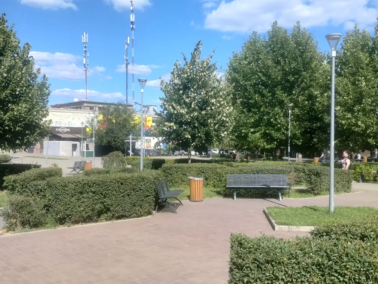 Літній Сквер Західний із зеленими живоплотами, лавами та кількома відвідувачами